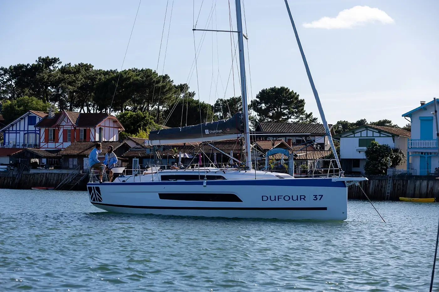 Seilbåt på vei inn mot en havn med trehus